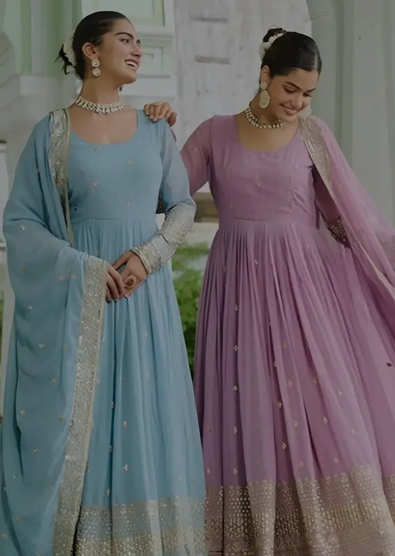 Two women in traditional outfits standing side by side with a blurred background