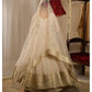 Traditional Indian bridal outfit with a white lehenga and gold dupatta on a neutral background.