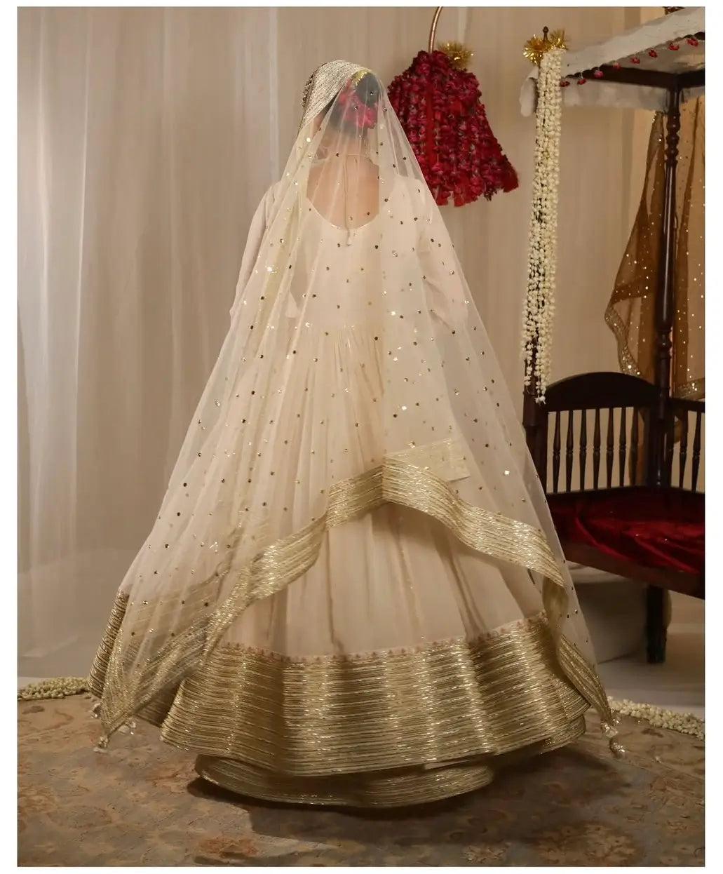 Traditional Indian bridal outfit with a white lehenga and gold dupatta on a neutral background.