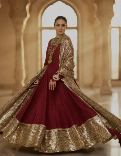 Deep magenta festive Anarkali outfit with detailed embroidery, styled in glowing wedding decor background for mobile hero image.