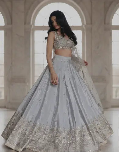 Silver grey bridal lehenga with heavy embroidered hem and embellished blouse, styled in a premium palace interior for mobile hero banner.